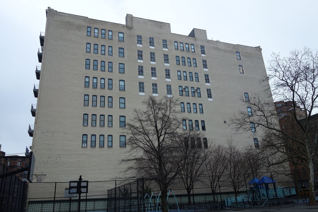 The pale brick loft building at 2 Gansevoort Street seen across the courts of Corporal John A. Seravalli Playground