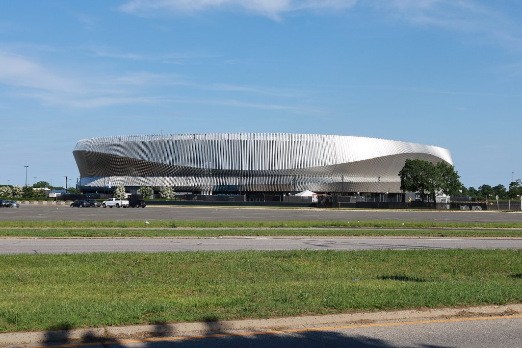 The silver-clad Nassau Veterans Memorial Coliseum in Uniondale seen across an open lawn